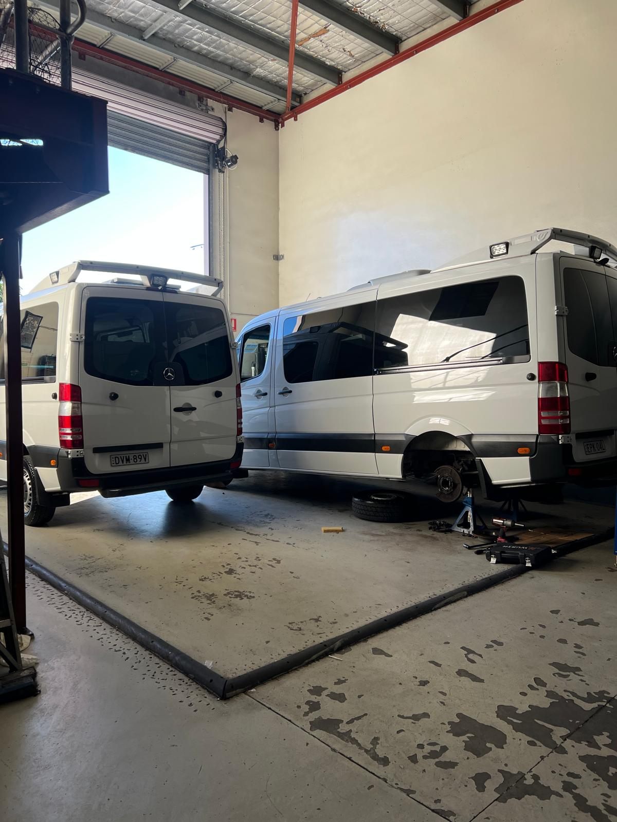 Two Mercedes Sprinter vans up on hoists for fleet servicing