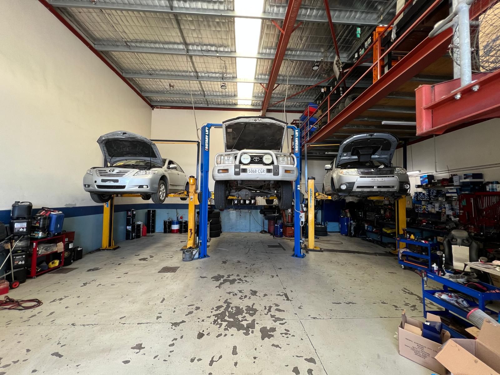 Inside the Orange Grove Automotive workshop, three vehicles up on hoists